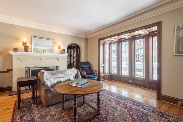 sitting room with ornamental molding, a brick fireplace, and light hardwood / wood-style floors