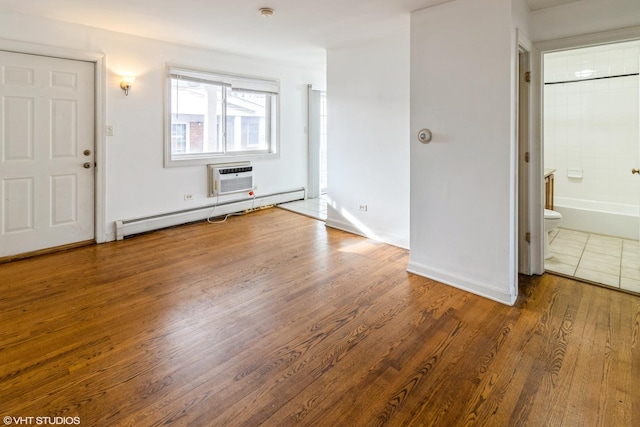 interior space featuring wood-type flooring, baseboard heating, and a wall unit AC