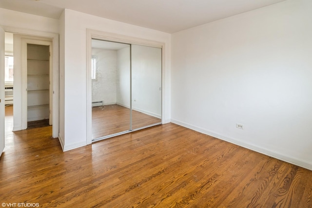 unfurnished bedroom with hardwood / wood-style flooring, a closet, and a baseboard radiator