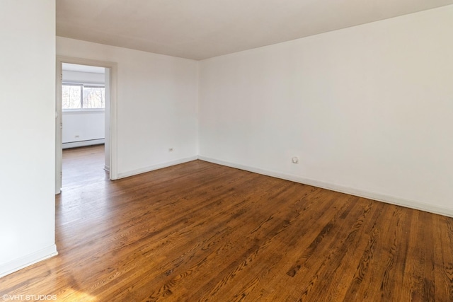 empty room with hardwood / wood-style flooring and baseboard heating