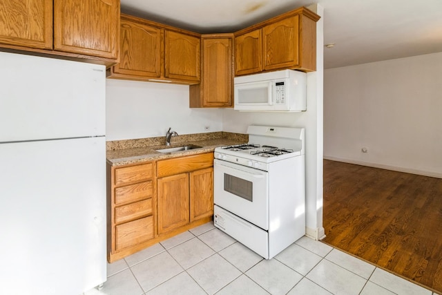 kitchen with sink, light tile patterned floors, and white appliances