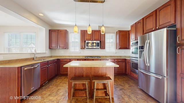 kitchen with appliances with stainless steel finishes, decorative light fixtures, sink, a center island, and plenty of natural light