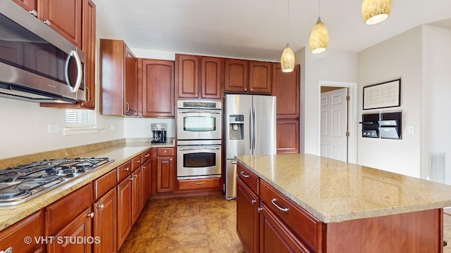 kitchen with light stone counters, hanging light fixtures, a center island, and appliances with stainless steel finishes