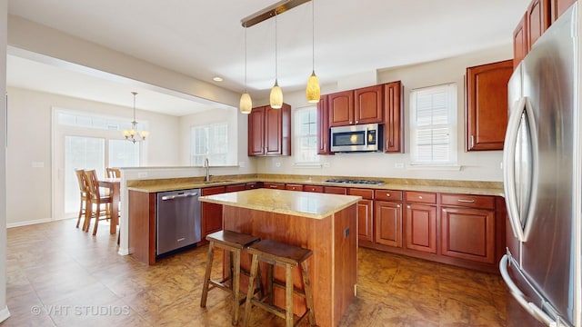 kitchen with a wealth of natural light, a kitchen breakfast bar, hanging light fixtures, a center island, and stainless steel appliances