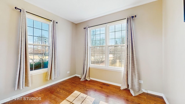 empty room with a healthy amount of sunlight and hardwood / wood-style floors