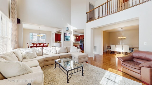 living room with a towering ceiling, a chandelier, and light hardwood / wood-style floors