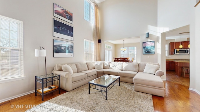 living room with an inviting chandelier, a towering ceiling, and hardwood / wood-style floors