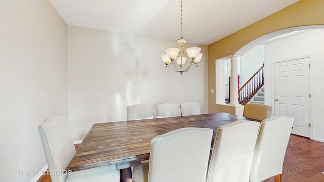 dining area with a notable chandelier, dark hardwood / wood-style flooring, and ornate columns