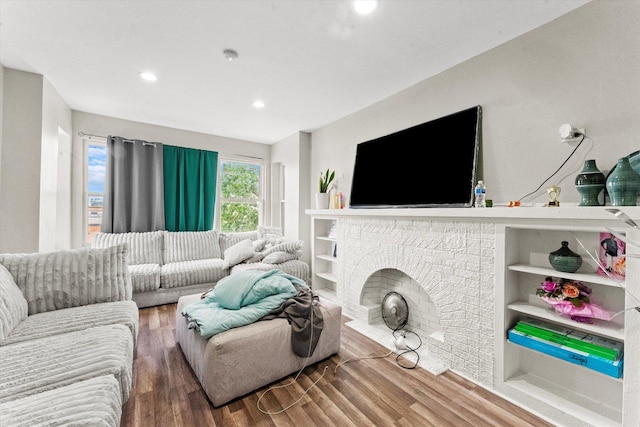 living room with a brick fireplace and hardwood / wood-style flooring