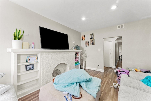 living room featuring wood-type flooring and a brick fireplace