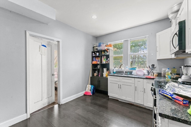 kitchen with dark wood-type flooring, white cabinets, range with electric cooktop, sink, and dark stone countertops