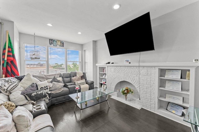 living room with built in shelves, wood-type flooring, and a fireplace