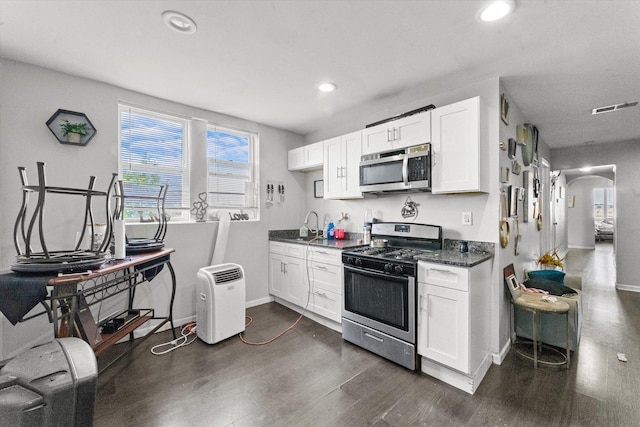 kitchen featuring sink, dark stone countertops, dark hardwood / wood-style flooring, white cabinetry, and stainless steel appliances