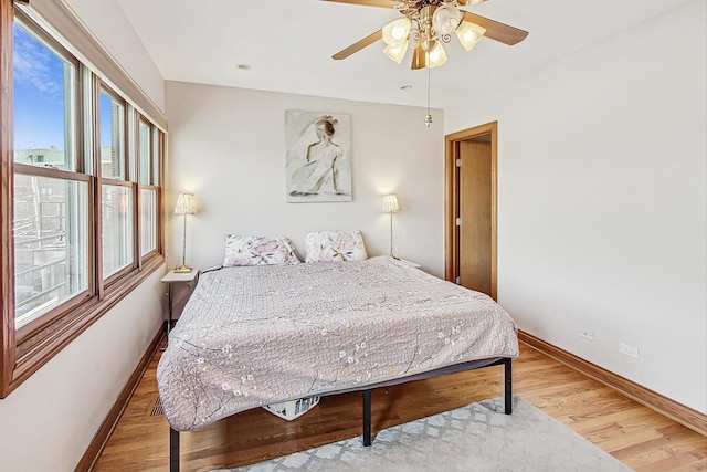 bedroom featuring multiple windows, hardwood / wood-style flooring, and ceiling fan