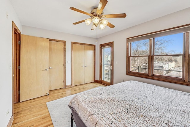 bedroom with ceiling fan, access to outside, light wood-type flooring, and two closets