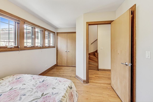 bedroom featuring multiple windows, light hardwood / wood-style floors, and a closet