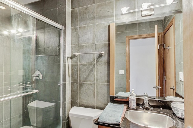 bathroom featuring a shower with door, vanity, tile walls, and toilet