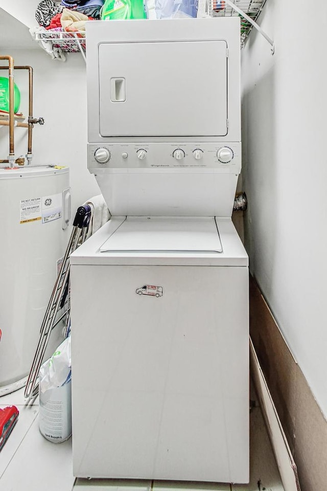 laundry room featuring electric water heater and stacked washer / dryer