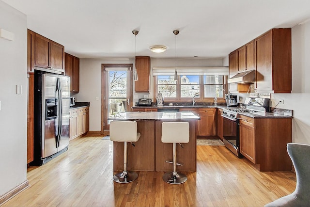 kitchen featuring stainless steel appliances, a center island, light hardwood / wood-style floors, and hanging light fixtures