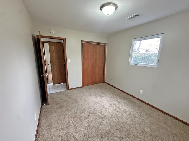 unfurnished bedroom with light carpet and a closet