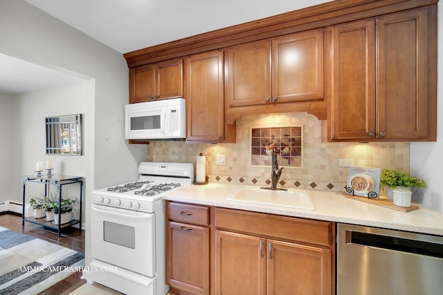 kitchen featuring white appliances, a baseboard heating unit, tasteful backsplash, and sink