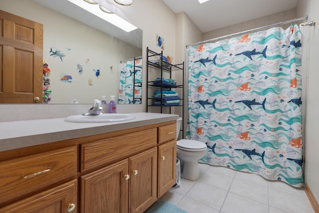 bathroom with toilet, vanity, a skylight, and tile patterned floors