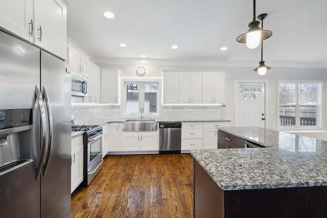 kitchen with white cabinets, appliances with stainless steel finishes, stone countertops, and sink