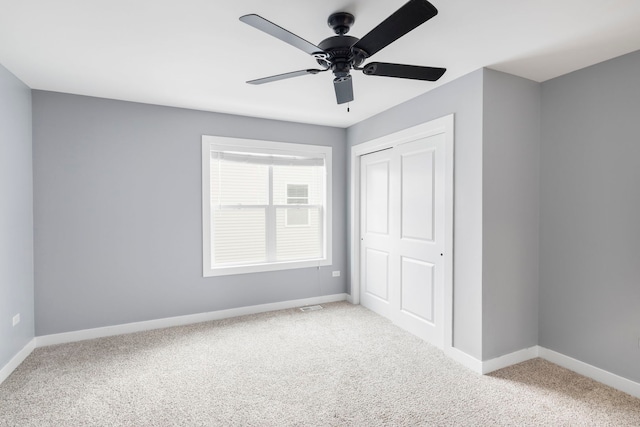 unfurnished bedroom featuring ceiling fan, a closet, and light colored carpet