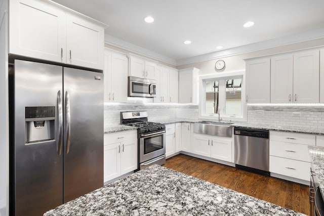 kitchen with tasteful backsplash, white cabinetry, sink, and appliances with stainless steel finishes