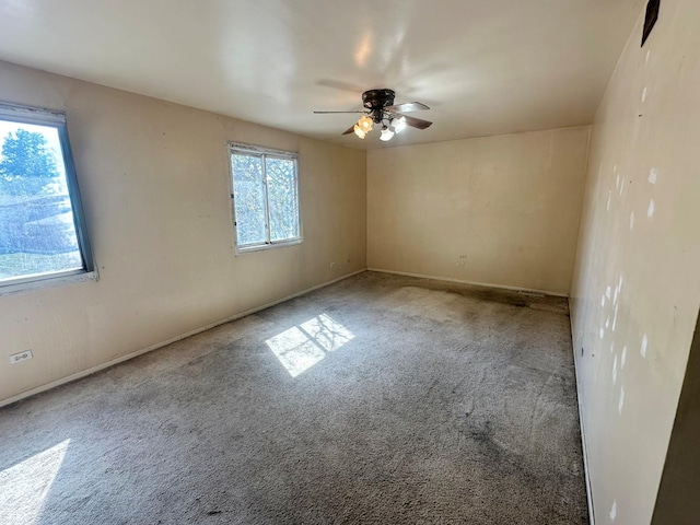 carpeted spare room featuring ceiling fan and a wealth of natural light