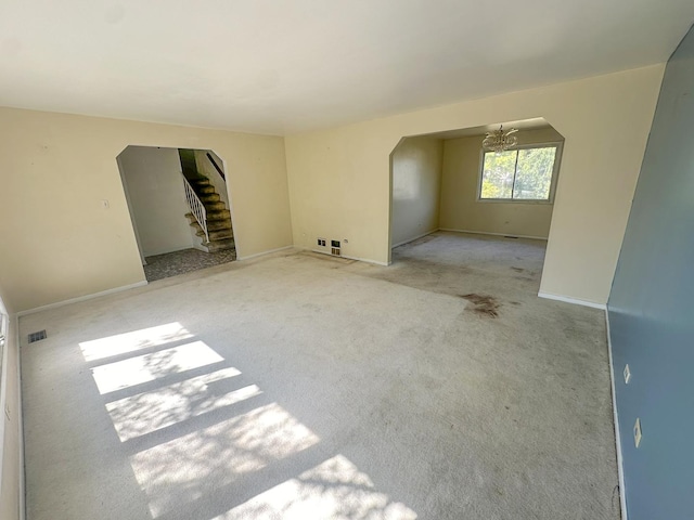 spare room featuring a chandelier and light carpet