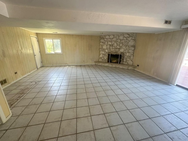 unfurnished living room with light tile patterned floors, a fireplace, and wooden walls