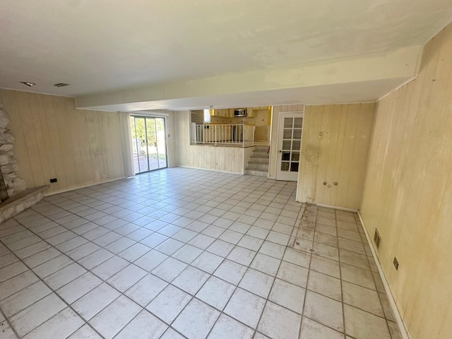 unfurnished living room featuring wooden walls and light tile patterned flooring