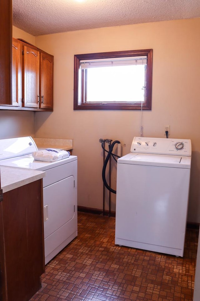 laundry room with washer and clothes dryer, cabinets, and a textured ceiling