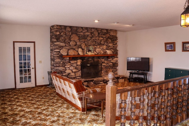 living room featuring a stone fireplace, carpet floors, and a textured ceiling