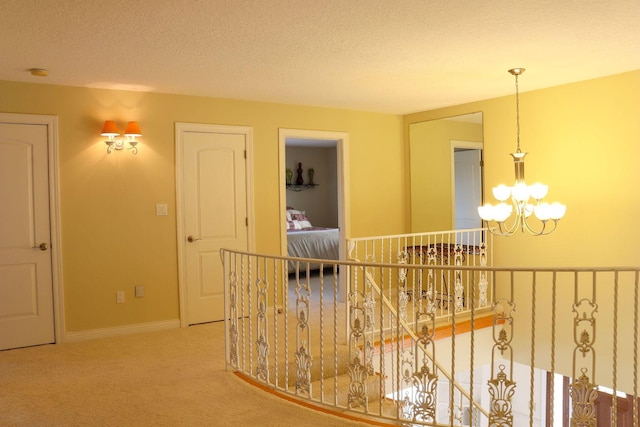 hallway with carpet, a textured ceiling, and a notable chandelier