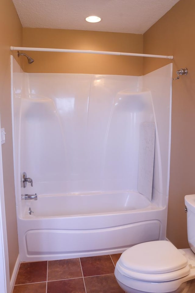 bathroom with bathing tub / shower combination, tile patterned flooring, a textured ceiling, and toilet