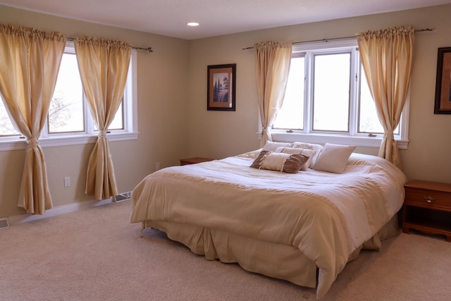 bedroom with multiple windows and light colored carpet