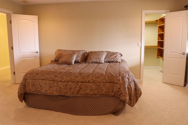 bedroom featuring a walk in closet, light carpet, and a closet