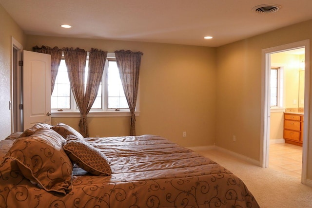 bedroom with light colored carpet and ensuite bath