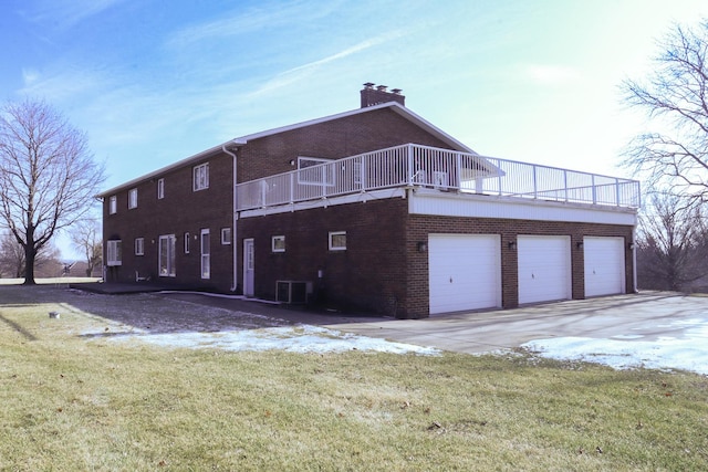 back of house featuring a lawn, a balcony, cooling unit, and a garage