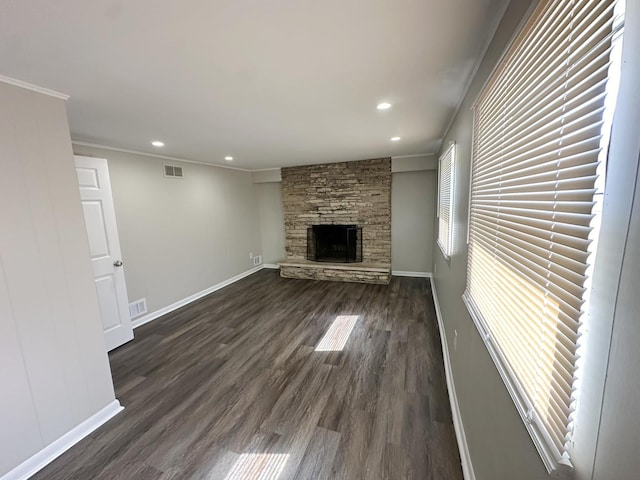 unfurnished living room featuring a stone fireplace, dark hardwood / wood-style flooring, and ornamental molding