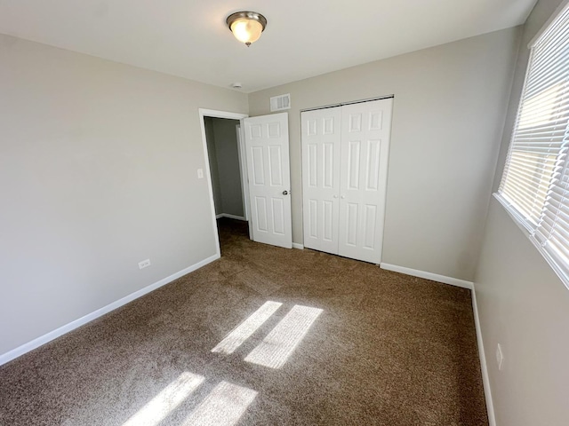 unfurnished bedroom with dark colored carpet and a closet