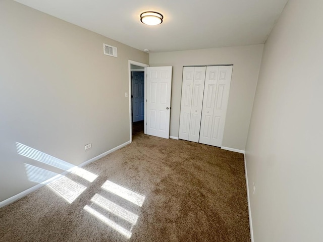 unfurnished bedroom with dark carpet and a closet