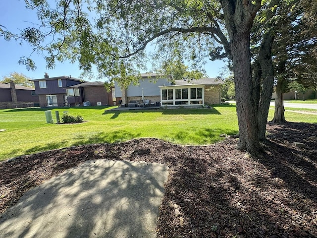 rear view of house with a lawn, a patio area, and a sunroom