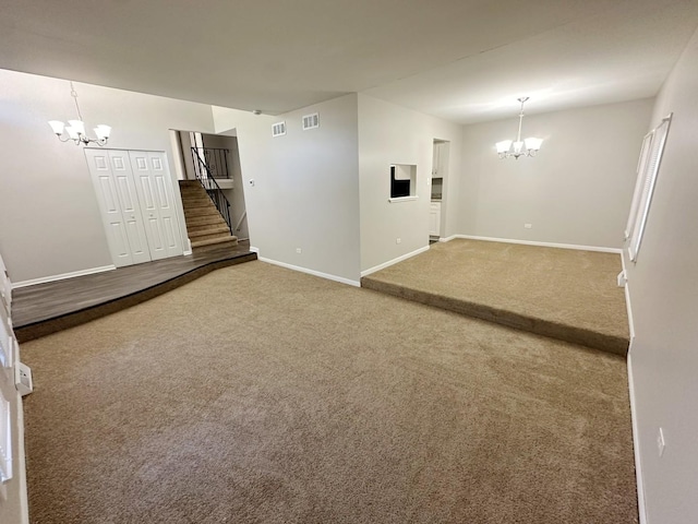 carpeted empty room featuring an inviting chandelier