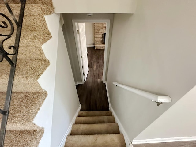 stairway with a fireplace and hardwood / wood-style floors