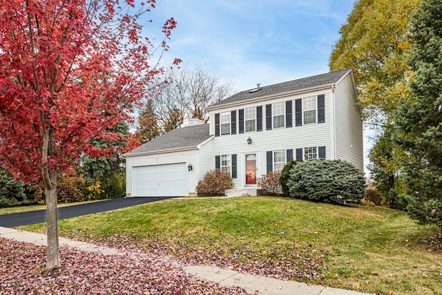 colonial inspired home with a garage and a front lawn