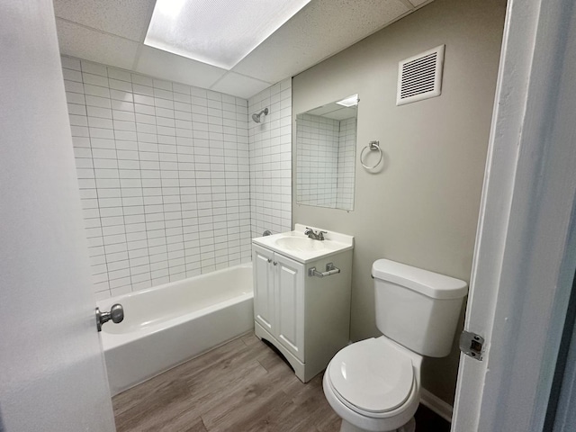 full bathroom with a paneled ceiling, vanity, hardwood / wood-style flooring, toilet, and tiled shower / bath