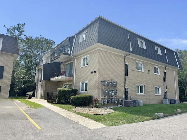 view of side of property featuring a lawn, cooling unit, and a balcony